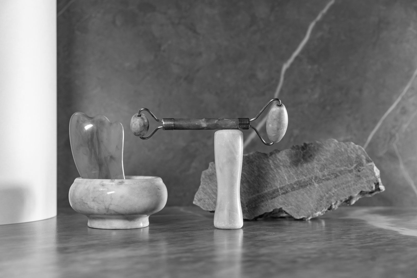 Rouleau de jade et gua sha sur marbre, en noir et blanc