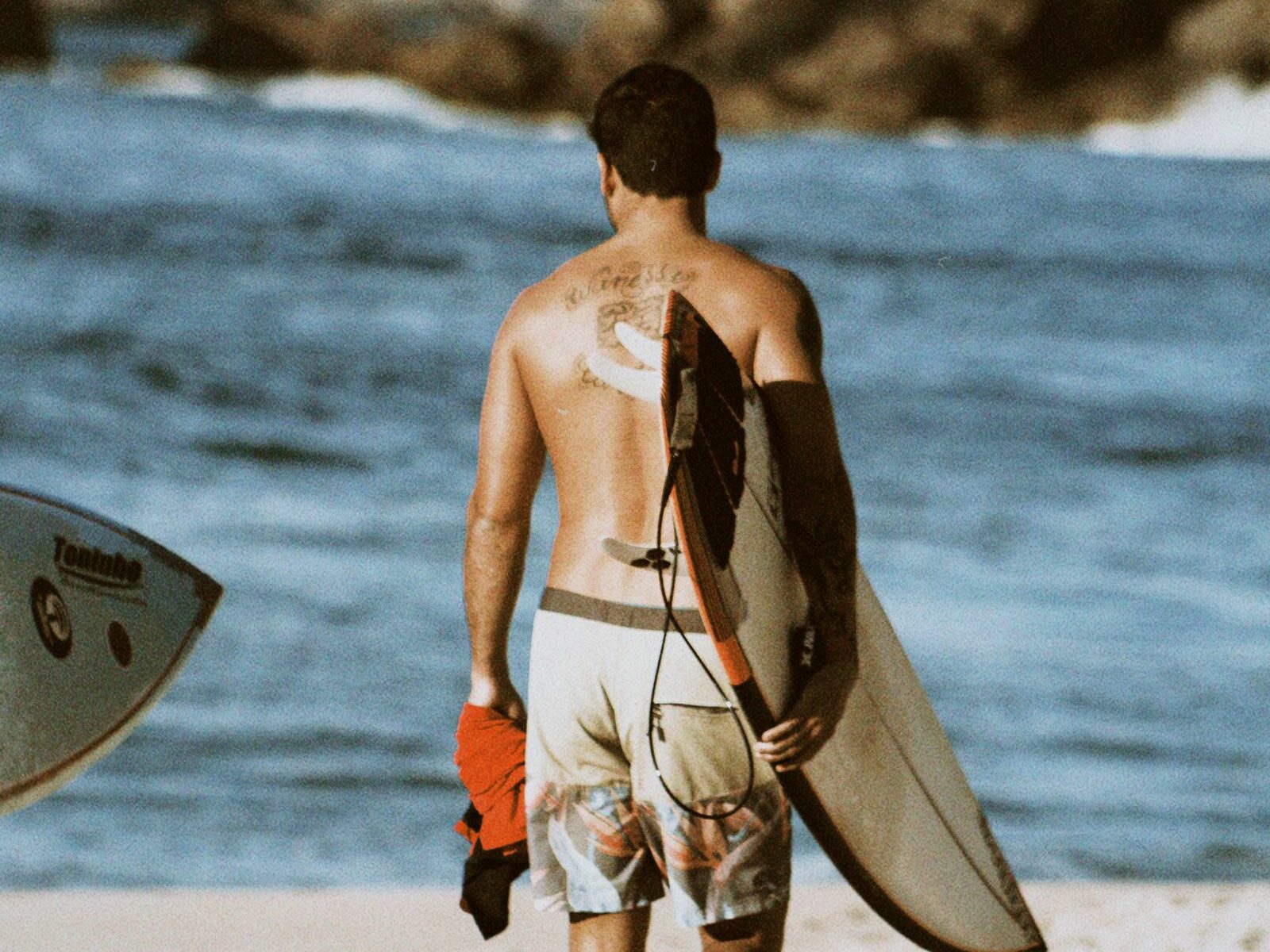 Homme avec une planche de surf sur une plage ensoleillée