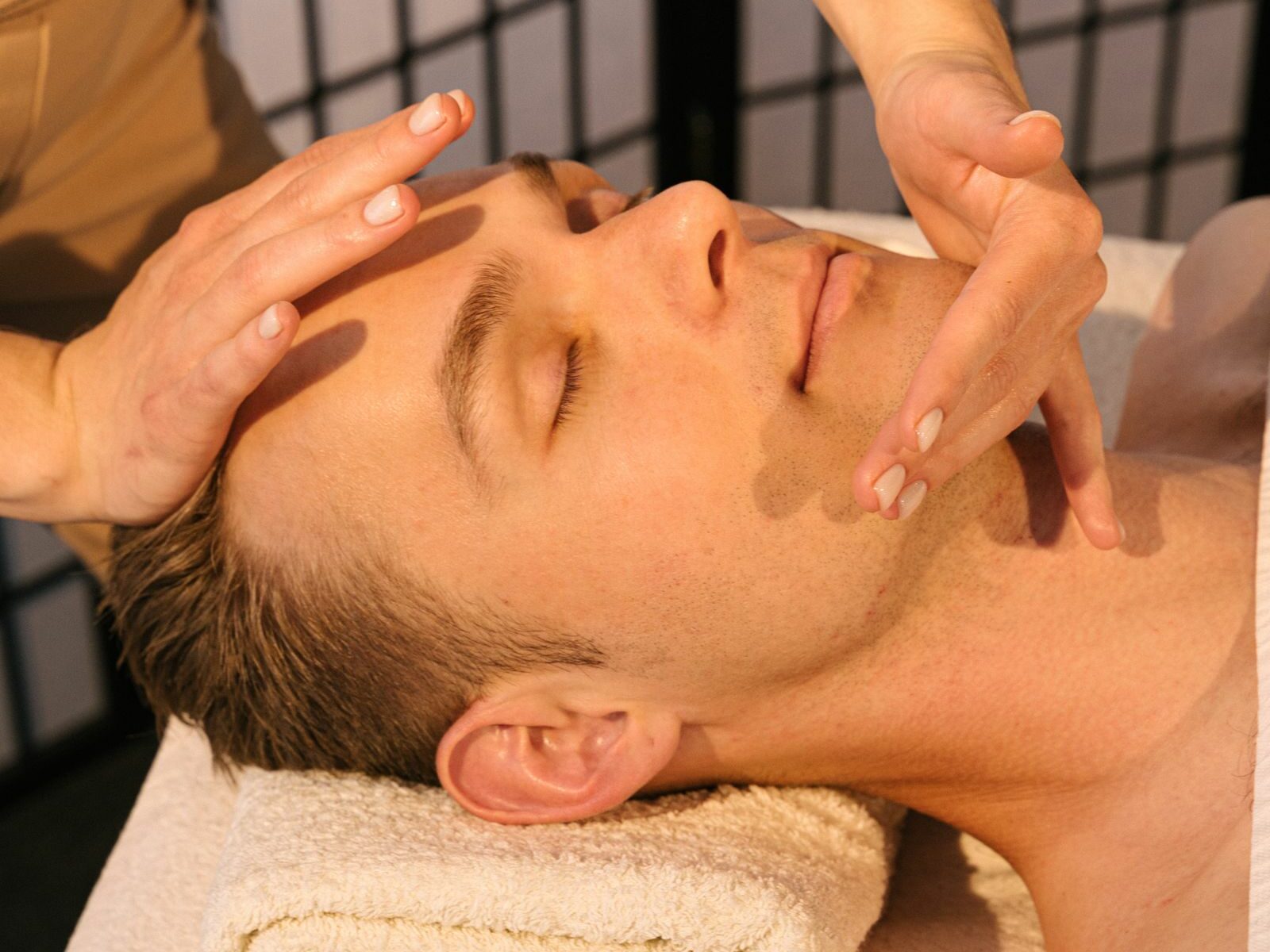Un homme reçoit un massage du visage en institut de soin
