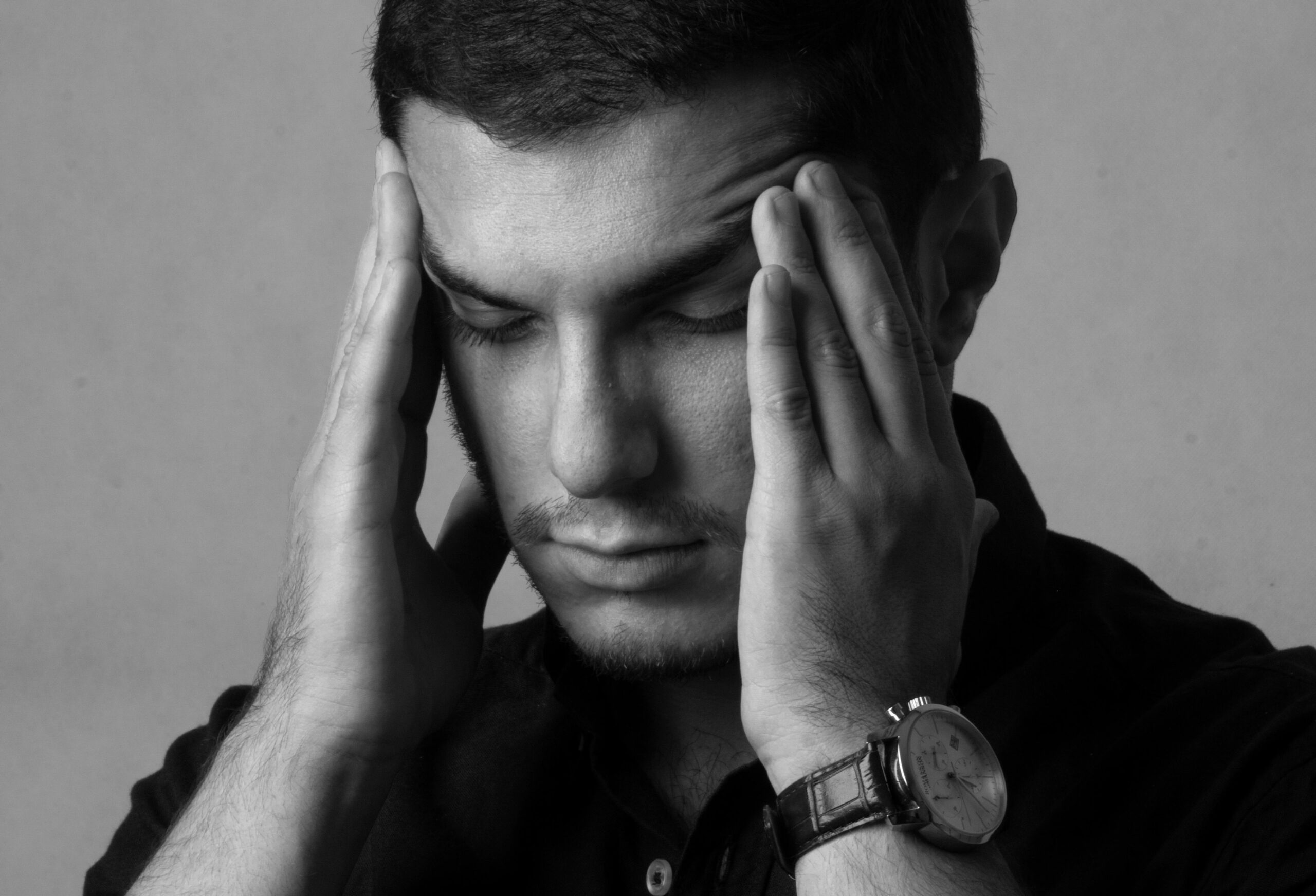 Angespannter Mann in Schwarz-Weiß, die Hände am Kopf, der Stress zeichnet das Gesicht