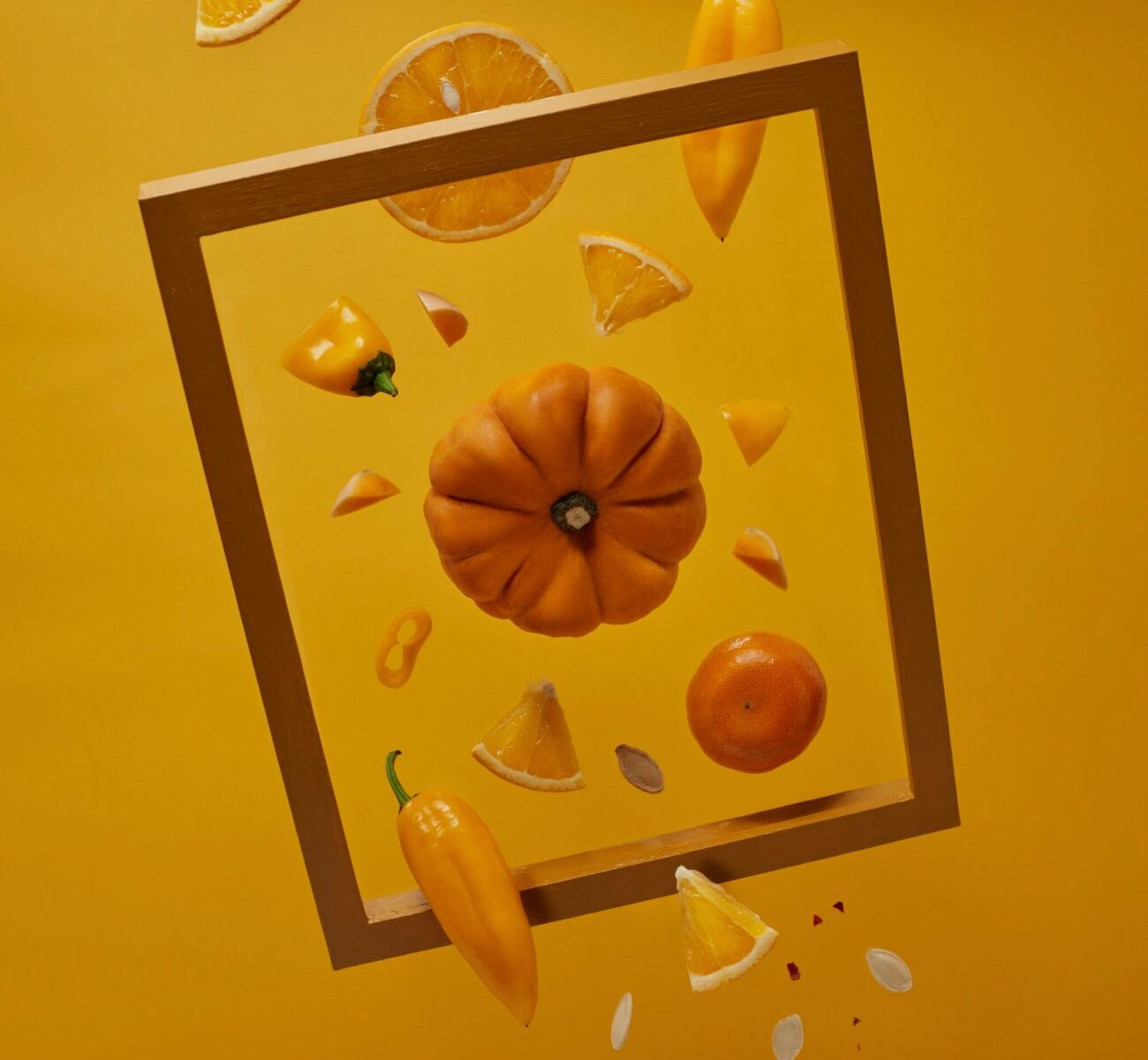 Fruits et legumes d'automne jaunes et oranges autour d'un cadre dore, energie et eclat de la peau